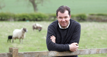 Guy Opperman in front of a field containing some sheep